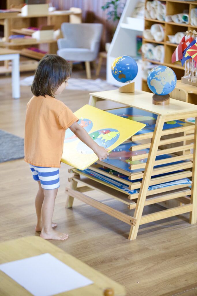 Niña explorando mapas y globos terráqueos en el ambiente Montessori